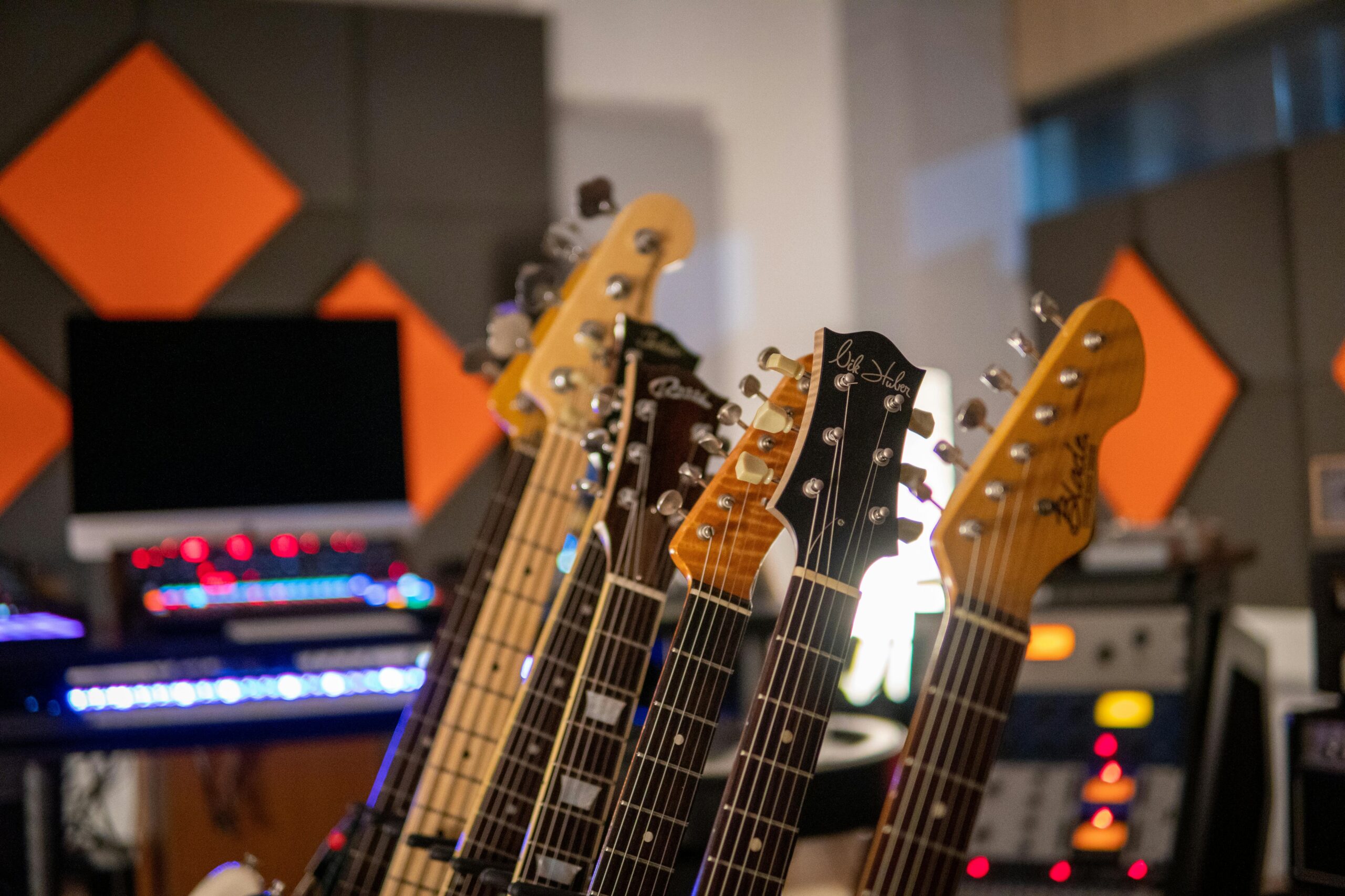 Close-up view of electric guitars lined up in a modern recording studio with vibrant acoustic panels.
